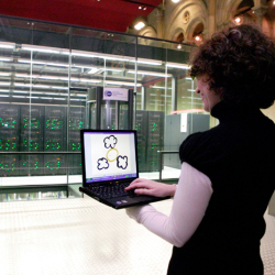 woman operates a laptop in front of a bank of computers