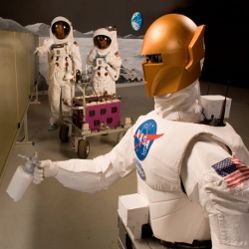 During a simulated lunar operation, NASA's Robonaut prototype welds a seam at a construction site while two moonwalking astronauts inspect completed work.