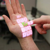 Wearable Depth-Sensing Projection System Makes Any Surface Capable of Multitouch Interaction