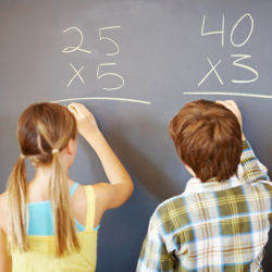 young girl and boy doing math at a blackboard