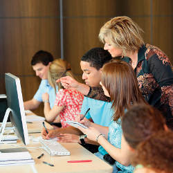 teacher with students at computers in classroom