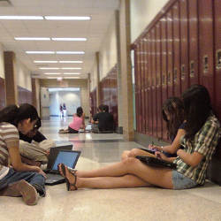 students using tablet computers in a school hallway