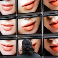 A woman watching multiple screens of facial expressions.