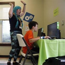 An instructor cheers on a camper at coding camp.