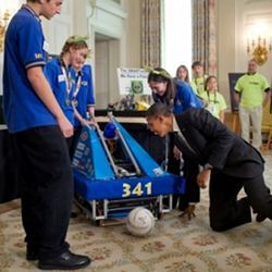 President Obama examines a soccer-playing robot. 