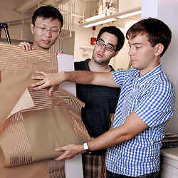 Three grad students demonstrate the flexibility of a radio built into a  plastic sheet. 