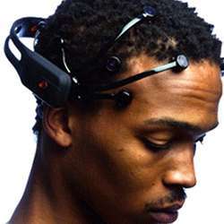 A man wearing the Emotiv EPOC headset, which reads EEG brain activity and transmits it wirelessly to a computer, which then sends signals to the robot to control its movements.