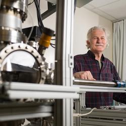 Walt de Heer, a Regents professor in the School of Physics at the Georgia Institute of Technology, poses with equipment used to measure the properties of graphene nanoribbons. 