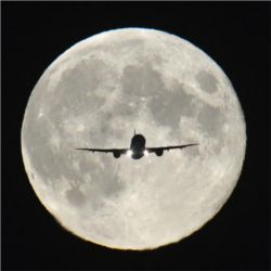 Plane flying in front of moon