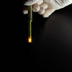 An organic light-emitting diode glows orange when electrical current flows through it.