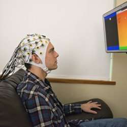 During a brain-to-brain interface demonstration, University of Washington student Darby Losey sends brain signals about firing a cannon in a computer game to a student in a different building.