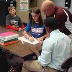 A teacher working with students on an engineering project. 