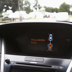 The 'Following Mode' icon is lit on the dashboard of an Acura RLX sedan being towed by another car with Honda virtual tow technology, which creates a wireless link between the two cars.