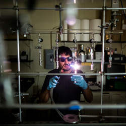 Ph.D. student Juan Lopez cuts a glass tube used in the production process for a new semiconductor compound.