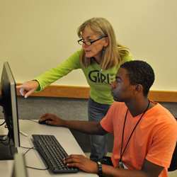 A high school computer science teacher works with a student.