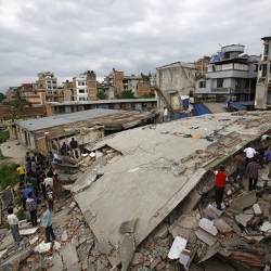 People gather near a collapsed house after a major earthquake in Kathmandu, Nepal, April 26, 2015. 