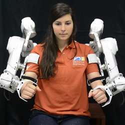 A woman demonstrates the HARMONY robotic rehabilitation exoskeleton.