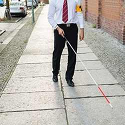 A visually impaired man uses a cane to find his way. 