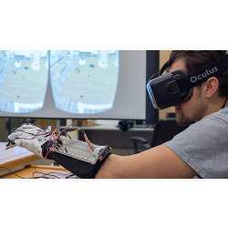 An engineering student explores a virtual scene with the aid of a headset and a haptic glove he and other undergraduates helped design. 