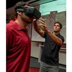 STriVR CEO Derek Belch adjusts the Rift virtual reality headset on Arkansas Razorbacks quarterback Brandon Allen.