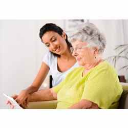 An elderly patient and a caregiver work with a tablet. 