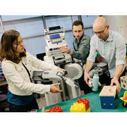 From left, Chelsea Finn, Sergey Levine, and Pieter Abbeel help the robot BRETT get a peg into a hole.