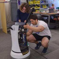 Two University of Pennsylvania students modify the Savioke Relay robot base by adding an arm for future manipulation tasks. 