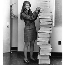 Margaret Hamilton standing next to a stack of Apollo Guidance Computer source code.