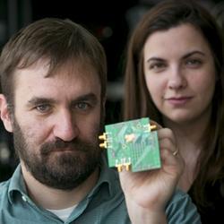 Associate professor Al Molnar and graduate student Hazal Yksel with a test board with the two-way transceiver chip mounted in the center. 