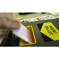 A voter feeds a ballot into a scanner.