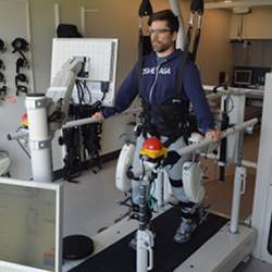 A patient uses rehabilitation robots to support and guide his steps to retrain his gait. 