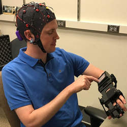 A medical resident tries out a device that detects electrical activity in his brain and causes his hand to open and close in response to brain signals.