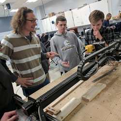 Monticello High School teacher Eric Bredder (left) confers with students using a CNC milling machine.