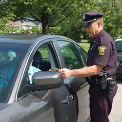 A police officer speaks with a driver during a traffic stop.