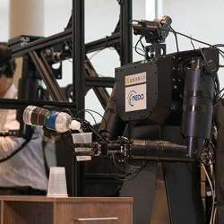 The robot pours water from a bottle into a cup.