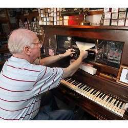 A user preparing an antique player piano for use. 