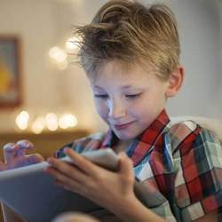 A boy accesses an app on a tablet. 