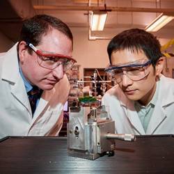 University of Connecticut researchers Michael Pettes, left, and Wei Wu check a specially engineered device they created to exert strain on a semiconductor material only six atoms thick.
