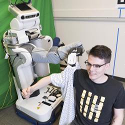 A robot puts a gown on a member of the research team.