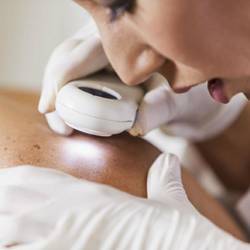 A dermatologist examines a patient's skin.