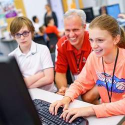 Professor David Fisher works with students during the Connecting with Code summer computing camp.