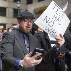 man holding sign stating 'Tech Has No Walls'