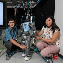 Researchers Amy Wu and Salman Faraji examine a robot's gait.