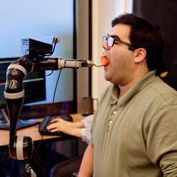 The robot feeds a doctoral student a strawberry.