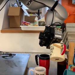 A robot hangs a coffee mug on a hook.