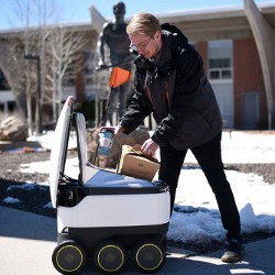 GMU student retrieves food from delivery robot