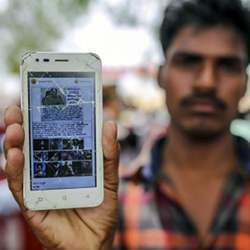 At an event in India to raise awareness of fake news, an attendee holds a mobile phone displaying a fake message shared on Facebook Inc.'s WhatsApp messaging service.