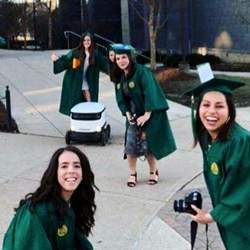 George Mason University graduates pose with a robot.