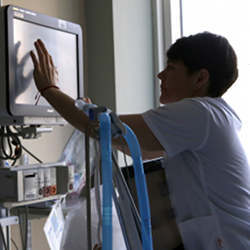 A nurse adjusts settings on a bedside patient monitor.