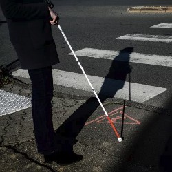 person with white cane in a crosswalk